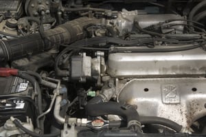 Under the hood of a car partial view of engine and battery, hoses, radiator, cables